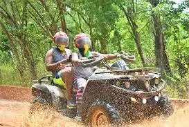 Guests riding an ATV on a wooded trail in Jamaica