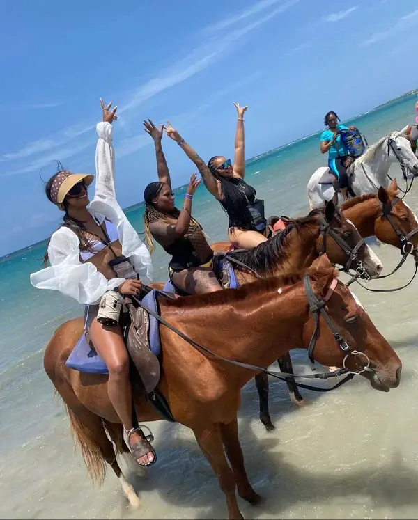 Guests riding horses through shallow Caribbean water